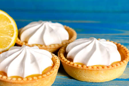 Lemon tartlets, Homemade shortbread mini tart cakes with lemon curd and whipped cream, blue background copy spaceの写真素材