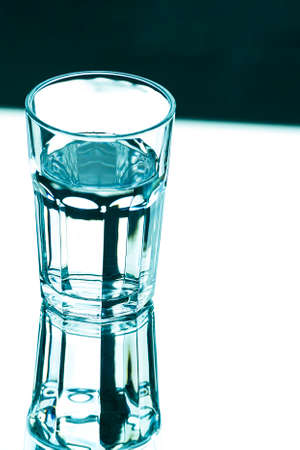 A glass with clean clear water with reflection and sharp shadows. top view.の写真素材