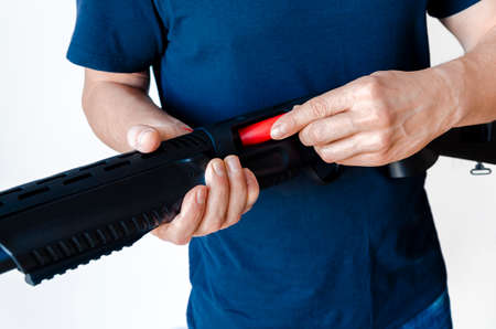 The man charges the shotgun with ammunition. Charging a pump smoothbore weapon. close-up photo.の写真素材