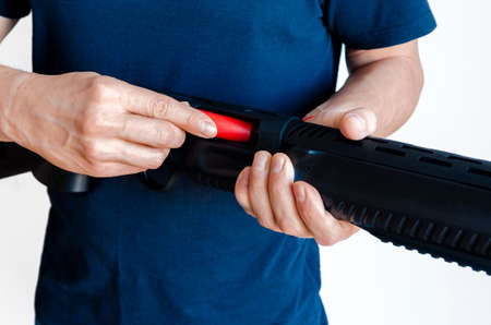 The man charges the shotgun with ammunition. Charging a pump smoothbore weapon. close-up photo.の写真素材