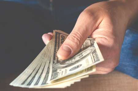 Hands passing money under table corruption bribery, businessman sealing the deal with a handshake and receiving a bribe money.の写真素材