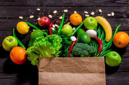 Different food in paper bag on wooden background, close up. Grocery shopping concept, top viewの写真素材