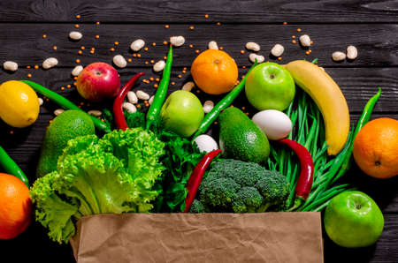 Healthy food selection. Shopping bag full of fresh vegetables and fruits. Flat lay food on tableの写真素材