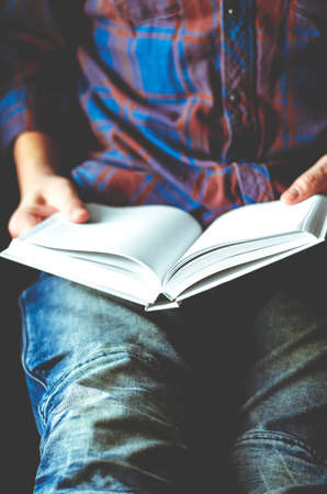 A man sits with a mock-up of a white book in his hands. close-upの写真素材