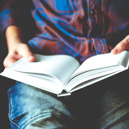 A man sits with a mock-up of a white book in his hands. close-upの写真素材