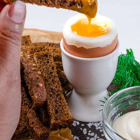 English breakfast with boiled egg and croutons on a white wood backgroundの写真素材