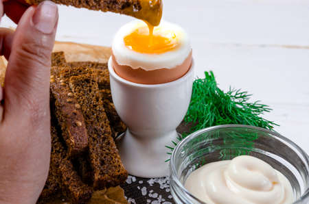 English breakfast with boiled egg and croutons on a white wood backgroundの写真素材