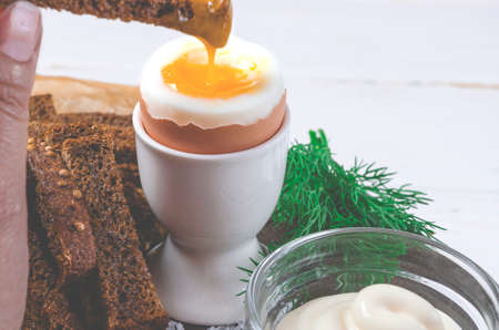 English breakfast with boiled egg and croutons on a white wood backgroundの写真素材