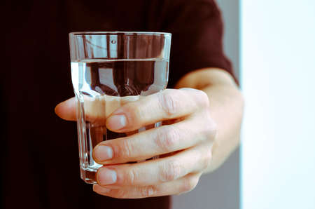 A mans hand with a glass of pure spring waterの写真素材