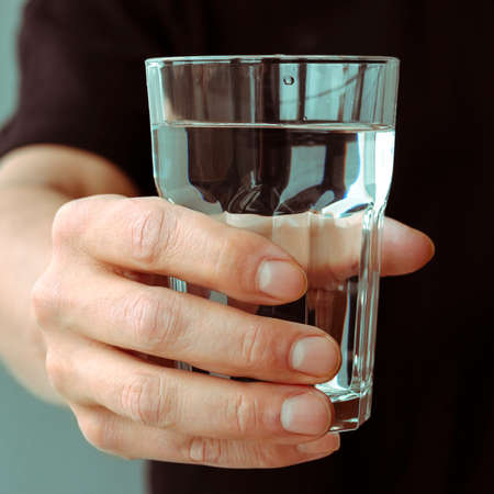 A mans hand with a glass of pure spring waterの写真素材