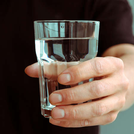 A mans hand with a glass of pure spring waterの写真素材