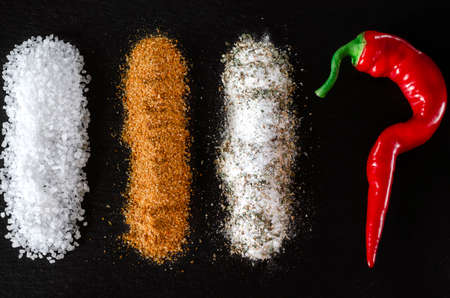 A set of spices, seasonings and salt lies on a black backgroundの写真素材