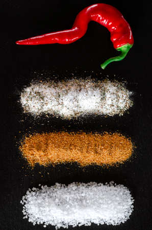 A set of spices, seasonings and salt lies on a black backgroundの写真素材