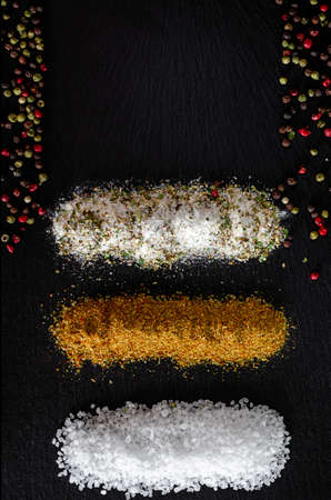 variety of natural and spicy salt on black tableの写真素材