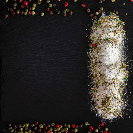Salt with herbs lies on a black stone with a place for textの写真素材