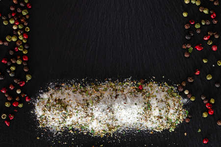 Salt with herbs lies on a black stone with a place for textの写真素材
