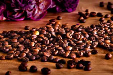 Roasted coffee beans scattered on a wooden tableの写真素材