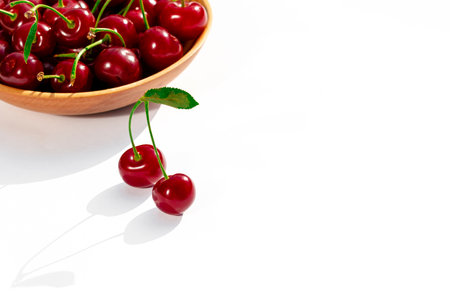cherry. Ripe red cherry with green leaves lies on a white backgroundの写真素材