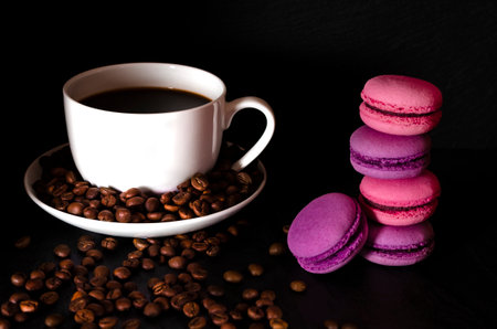 coffee. A white cup of coffee stands on the table next to the coffee beans on a black background.の写真素材