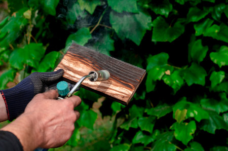 Professional carpenter using old traditional technique. Burning wood planks with gas burnerの写真素材