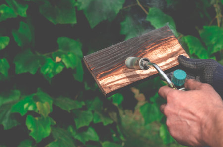 Professional carpenter using old traditional technique. Burning wood planks with gas burnerの写真素材
