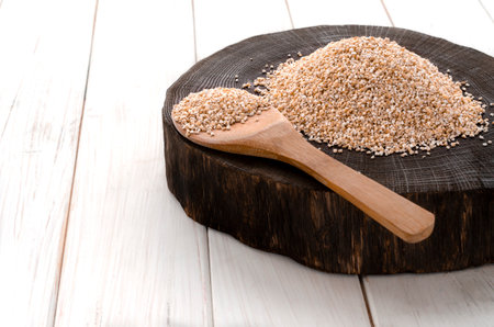 A healthy way of life. Coarse barley grits on a round wooden boardの写真素材