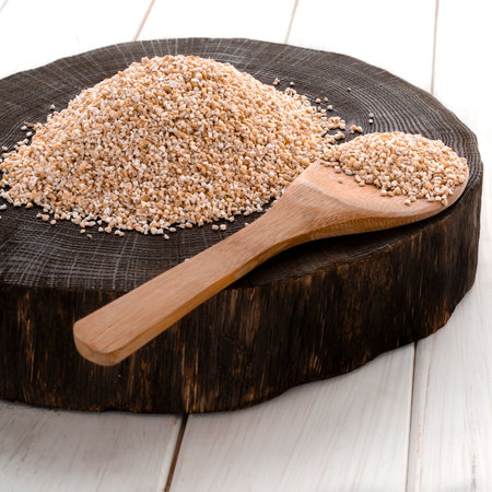 A healthy way of life. Coarse barley grits on a round wooden boardの写真素材