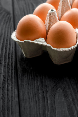 Brown chicken eggs in a cardboard tray on a wooden tableの写真素材