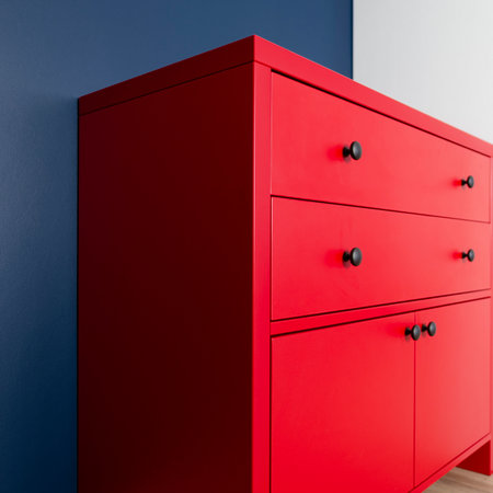 New red chest of drawers in the interior of the apartment against the background of a blue wall and a white wardrobeの写真素材
