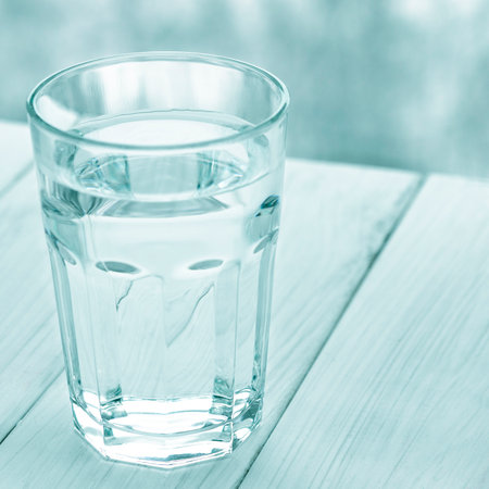 A glass of pure spring water stands on a white wooden backgroundの写真素材