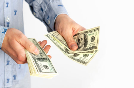Businessman in blue shirt counts bills for 100 dollarsの写真素材