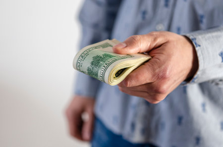 A man hands over a thick wad of dollarsの写真素材