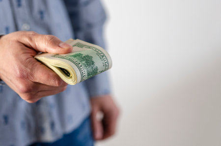 A man gives a bribe. A thick pack of dollars in the hands of a manの写真素材