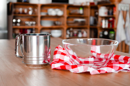 kitchen content. A cup-sieve for flour stands on a wooden tableの写真素材