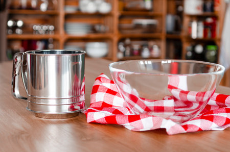 kitchen content. A cup-sieve for flour stands on a wooden tableの写真素材