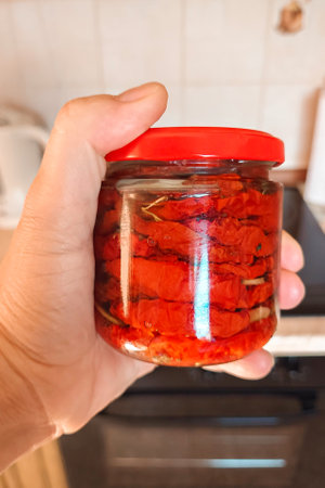 Red dried tomatoes in a jar in a womans handの写真素材