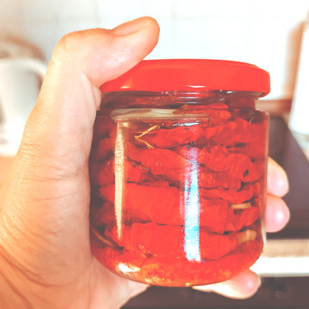 Red dried tomatoes in a jar in a womans handの写真素材