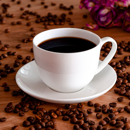 A white porcelain cup with black coffee stands on a wooden table. Coffee beansの写真素材