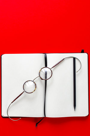 Round vintage glasses, black pencil and white notebook on table. Backgroundの写真素材