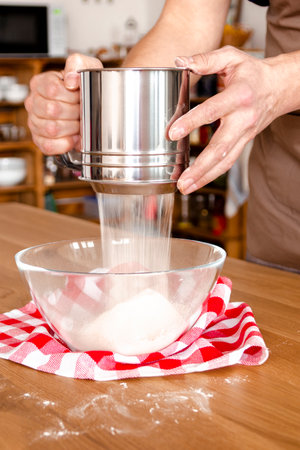 Pouring flour into the glass bowl as an essential ingredient for the recipeの写真素材