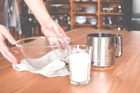 Hand grabbing something from a glass bowl on a wooden table