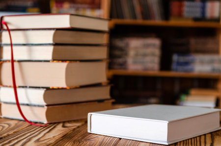White book on a wooden table against the background of bookshelvesの写真素材