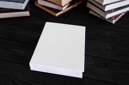 White book with space for text on a black table against the background of old books. Education...