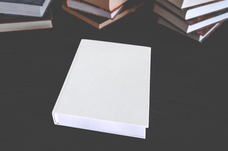 White book with space for text on a black table against the background of old books. Education conceptの写真素材