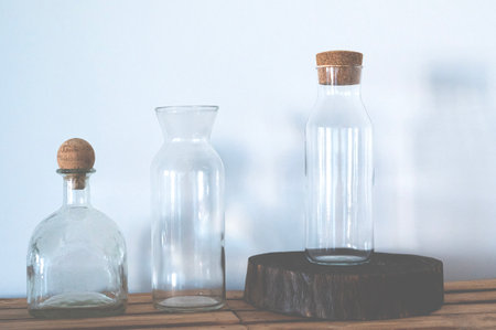 Textured glass bottles stand on near a white wallの写真素材