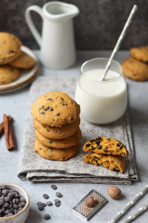 Soft pumpkin chocolate chip cookies with a glass of milk on a grey napkin. Grey concrete base and dark backround.の写真素材
