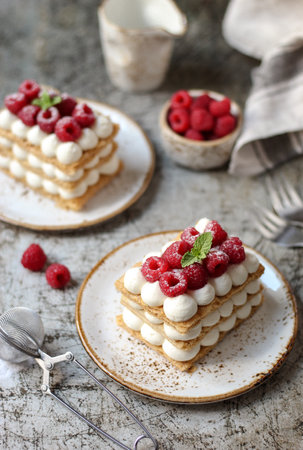 Raspberry Mille-feuille. Classic French pastry made of 3 layers of puff pastry with silky vanilla cream. Rusty, metallic, scratched base, fresh raspberries, and grey napkin.の写真素材