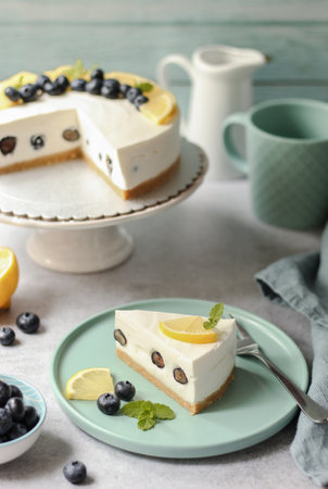 Slice of a lemon and blueberry cheesecake on a turquoise plate. Delicious, no baked, summer dessert. Grey base and turquoise background.の写真素材