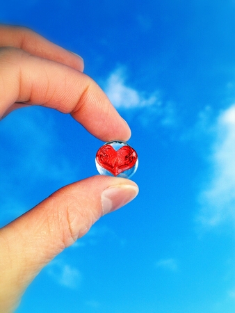 Glass ball in hand against the skyの写真素材