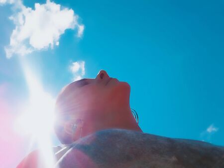 The girl in the sun on a blue sky backgroundの写真素材
